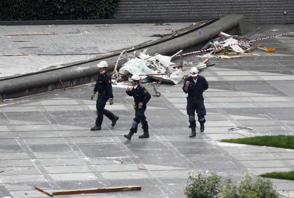 Norwegian policemen inspect the blast site in front of the destroyed government building in Oslo