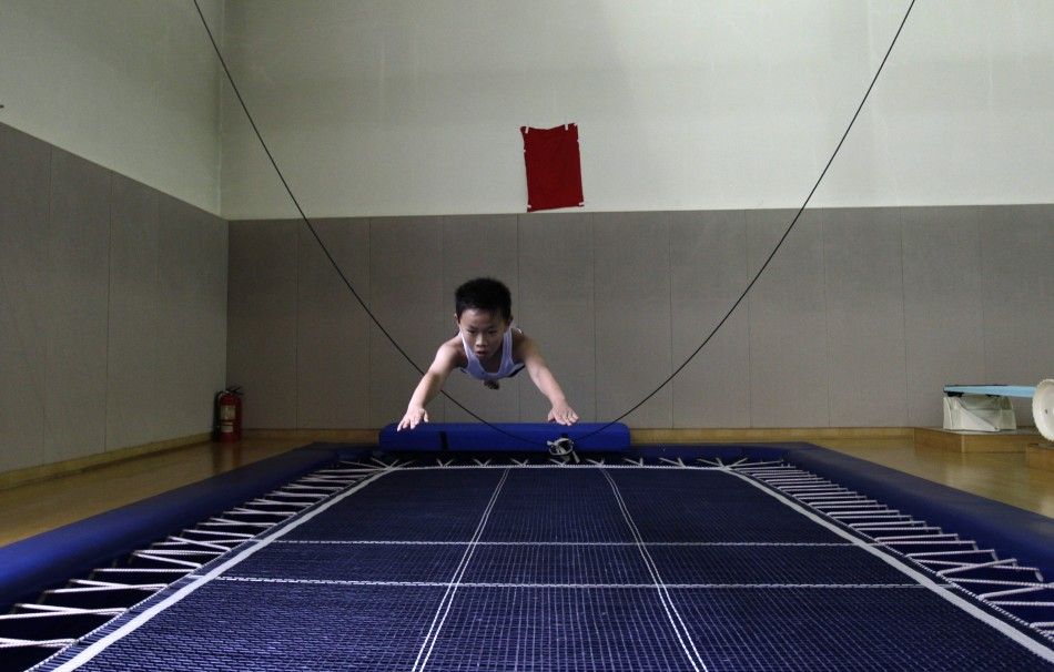 A boy practises his diving posture on a trampoline during a diving training session at a training centre in Beijing