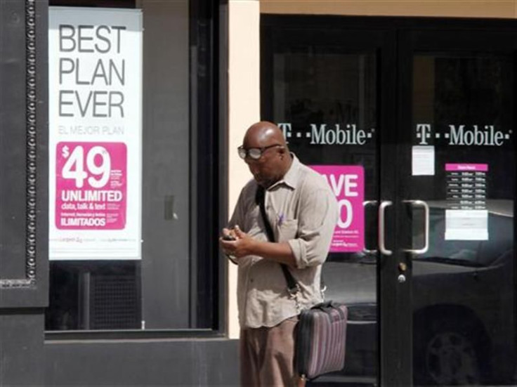 A man checks his mobile phone as he walks past a T-Mobile store in downtown Los Angeles