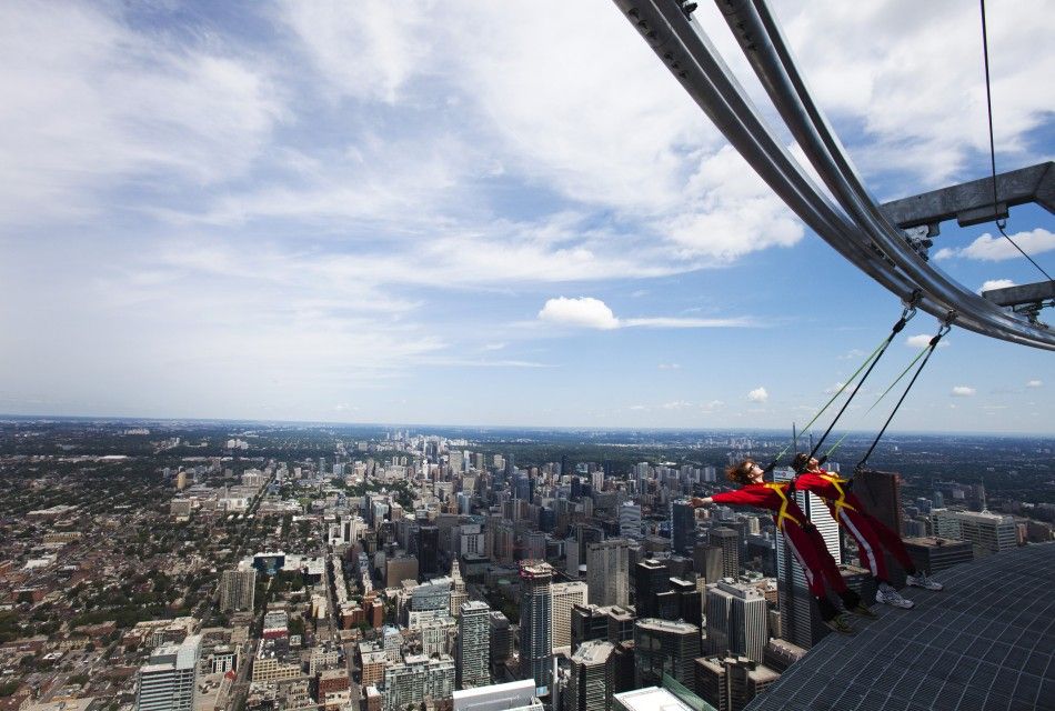 A reporter leans over the edge of the catwalk during the media preview for the quotEdgeWalkquot on the CN Tower in Toronto