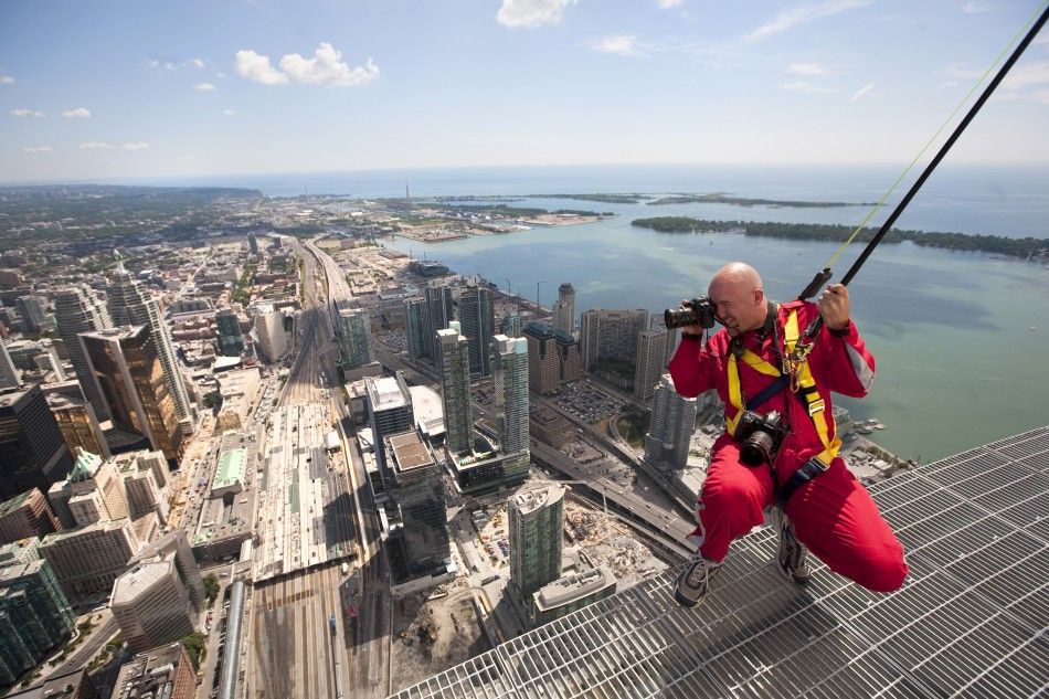 Photographer Mark Blinch works on the catwalk during the media preview for the quotEdgewalkquot on top of the CN Tower in Toronto