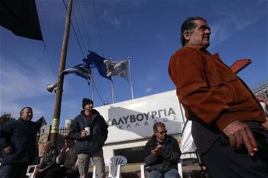 Workers of the Hellenic Steel Company stand outside a factory during a strike at Aspropyrgos