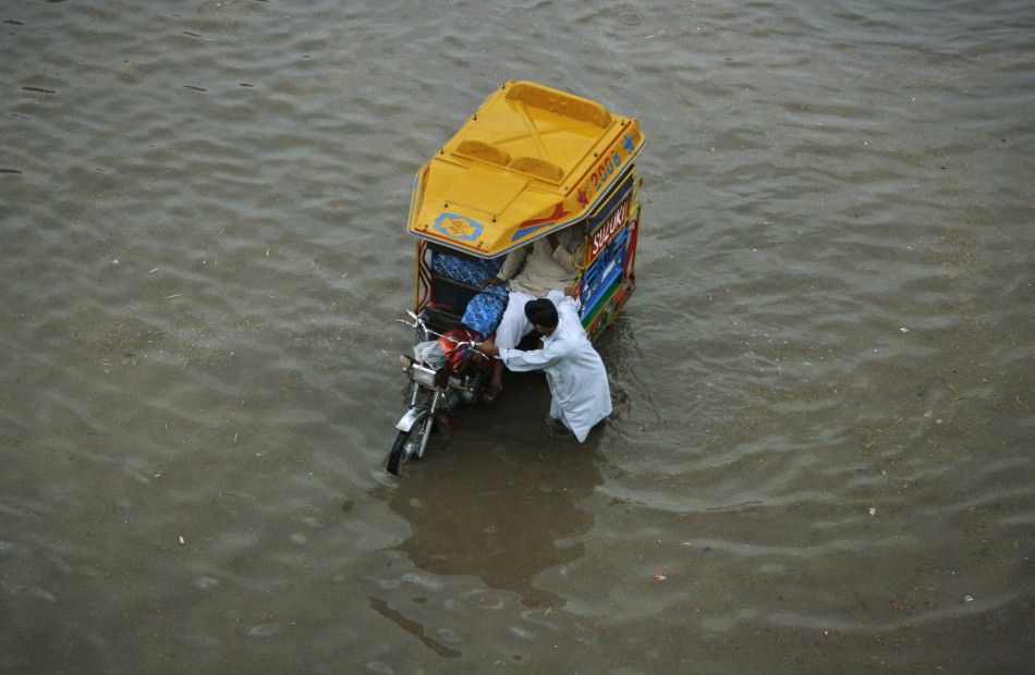 A man pulls his motorcycle rickshaw while transporting commuters through a flooded street, after a heavy downpour in Faisalabad