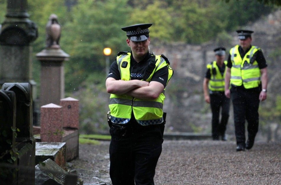 Police patrol the grounds as preparations begin for the wedding of Zara Phillips and Mike Tindall, at the entrance to the Canonngate Kirk in Edinburgh, Scotland 