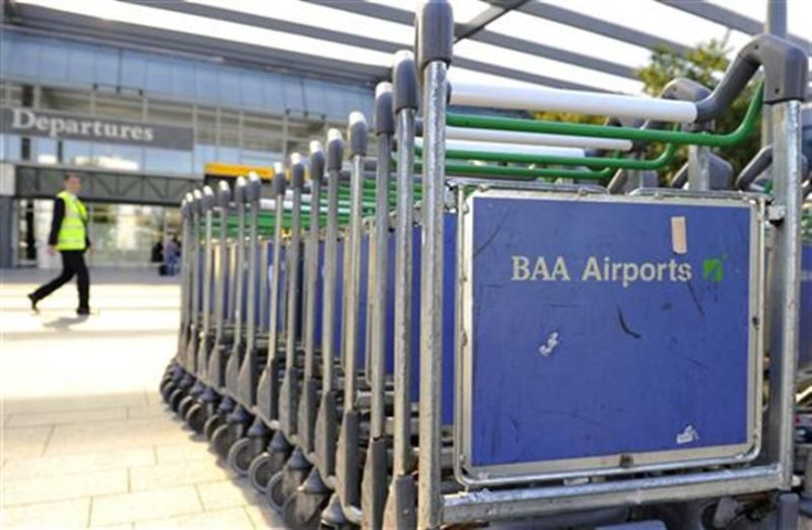 A worker passes luggage trollies at Heathrow Airport in London