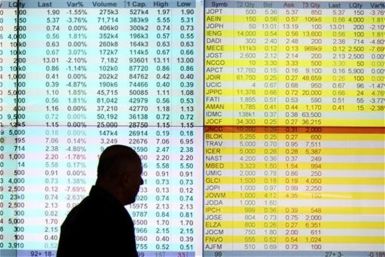 A dealer walks past an electronic board in the investors' gallery at the Amman Stock Exchange November 21, 2011.