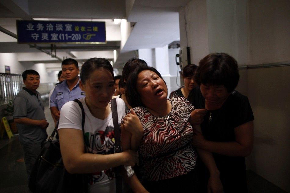 A woman cries as relatives console her inside a morgue where people had gathered to search for their missing kin who were passengers on two bullet trains that had crashed in Wenzhou, Zhejiang province