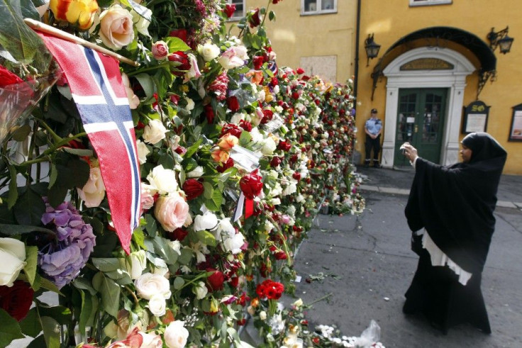 A Muslim woman takes pictures near a sea of floral tributes placed outside the Oslo Cathedral