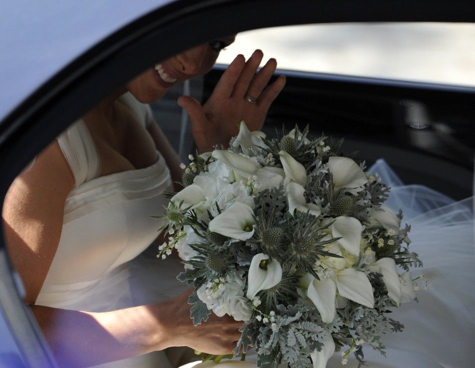 Britains Zara Phillips waves while holding her bouquet as she sits in a car after her marriage to England rugby captain Mike Tindall at Canongate Kirk in Edinburgh