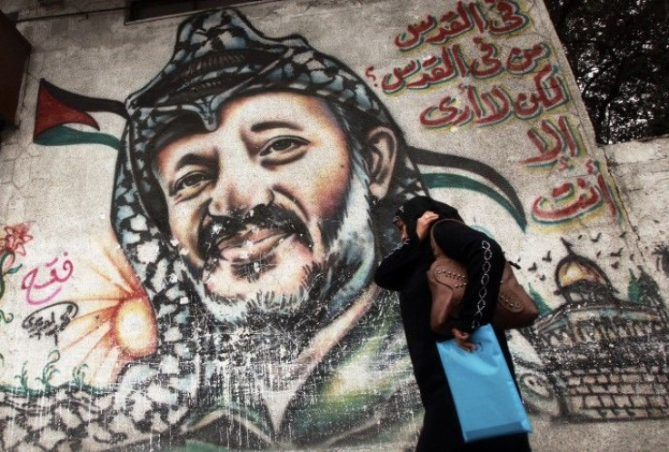 Palestinian woman walks past a mural depicting late Palestinian leader Arafat in Gaza City