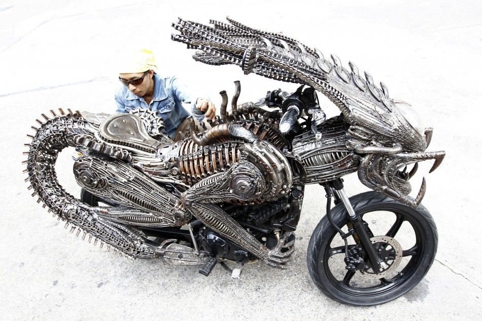 A worker checks the finishing on a motorcycle made from recycled materials of spare parts from cars and bicycles at a workshop in Bangkok