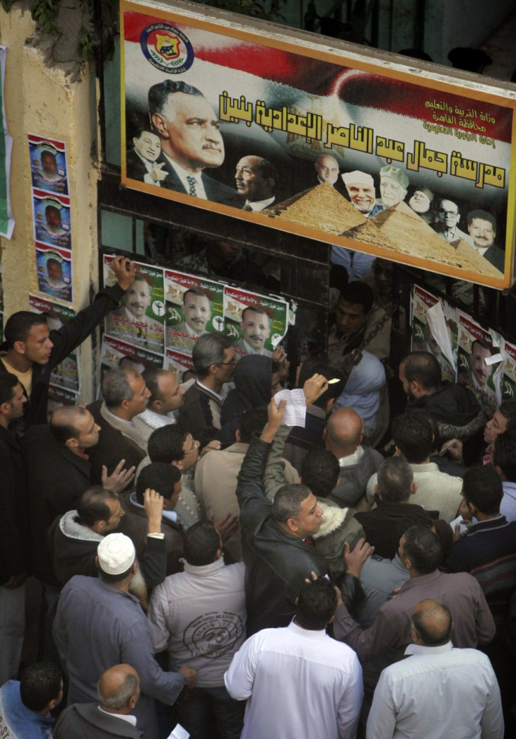 People stand outside a polling station as they wait to cast their votes during parliamentary elections in Cairo