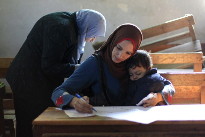 An Egyptian woman reads a ballot paper before casting her vote at a polling station during the parliamentary election in Cairo
