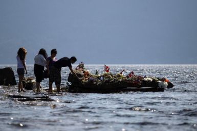 People offer flowers on a memorial stone in Tyrifjorden lake near Utoeya island