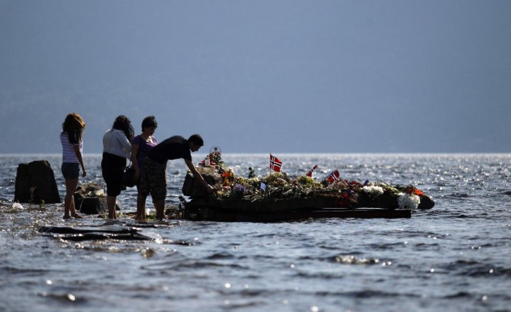 People offer flowers on a memorial stone in Tyrifjorden lake near Utoeya island