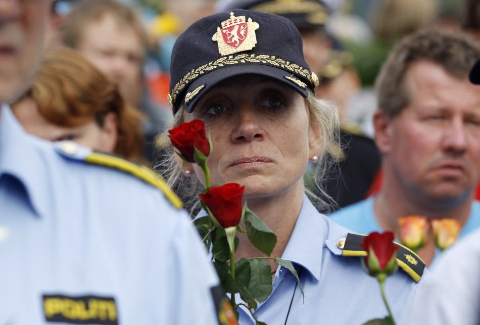 A police woman holds flowers as she takes part in a march near Utoeya island to pay their respects for the victims of the killing spree and bomb attack in Norway, in the village of Sundvollen