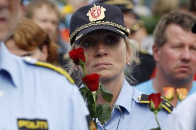 A police woman holds flowers as she takes part in a march near Utoeya island to pay their respects for the victims of the killing spree and bomb attack in Norway, in the village of Sundvollen