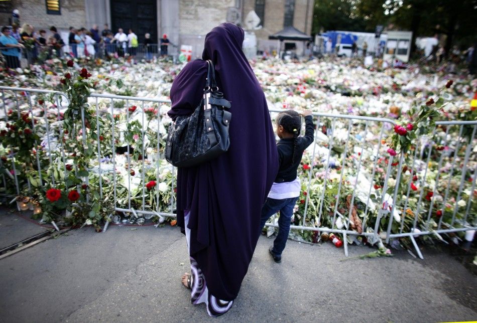 A Muslim woman pays her respects for the victims of last Friday039s attacks in front of a sea of flowers outside the Oslo cathedral