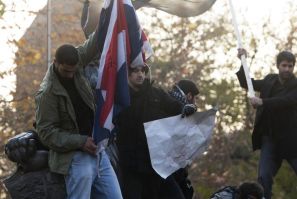 A protester tries to set fire to a British flag on top of a wall at the British embassy in Tehran