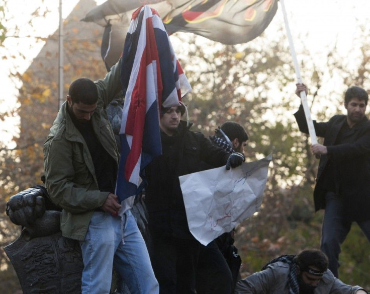 A protester tries to set fire to a British flag on top of a wall at the British embassy in Tehran