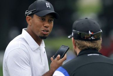Tiger Woods of the U.S. holds his cell phone as he speaks with another golfer on the driving range during a practice day for the WCG Bridgestone PGA tournament at Firestone Country Club in Akron
