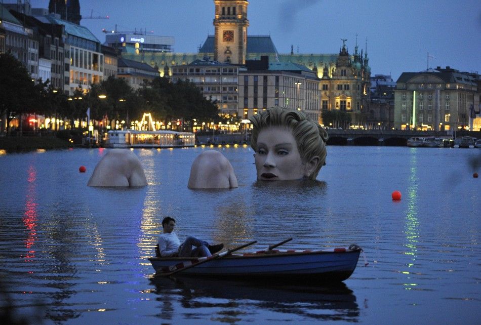 A man in a rowing boat floats near a 039mermaid039 sculpture created by Oliver Voss on Alster lake in Hamburg in the late evening