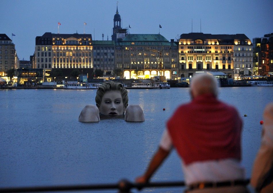 A man looks at a 039mermaid039 sculpture created by Oliver Voss in the late evening hours on Alster lake in Hamburg
