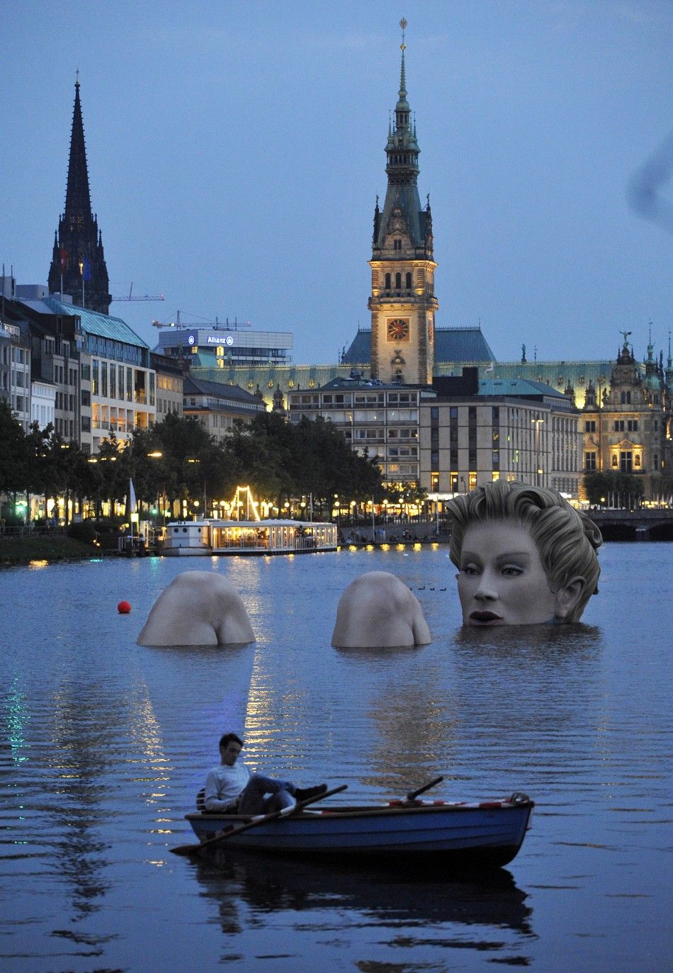 Man in a rowing boat floats near a 039mermaid039 sculpture created by Oliver Voss on Alster lake in Hamburg