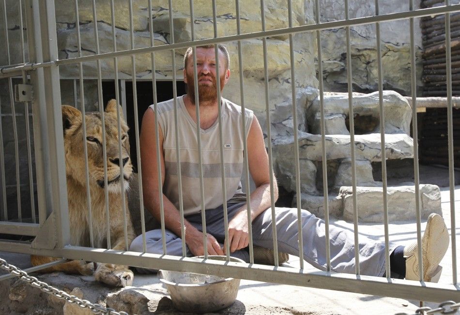 Zoo owner Pylyshenko sits inside a cage with female African lion Katya at a private zoo situated in his yard in Ukraine