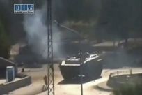 Smoke is seen near a tank at Al-Bahra roundabout in Hama in this still image taken from video