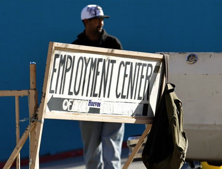 A day labourer stands behind a sign for an employment center in San Diego