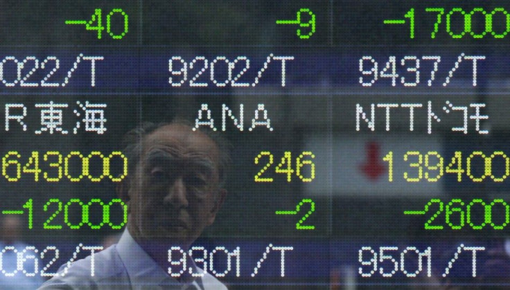 A man's reflection is seen on an electronic stock quotation board outside a brokerage in Tokyo