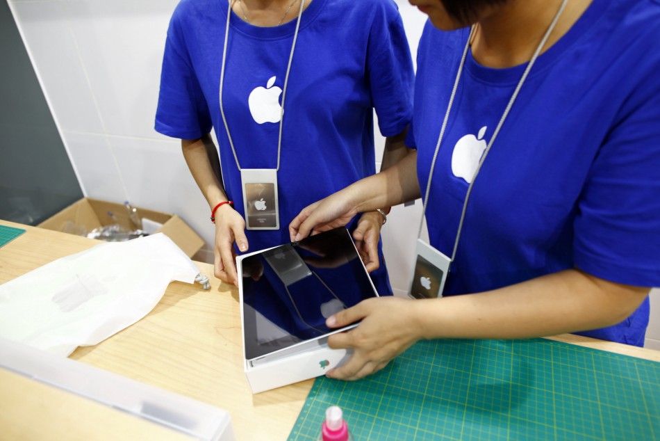 Employees look at a new iPad 2, purchased by a customer inside a fake Apple Store in Kunming, Yunnan province July 22, 2011.