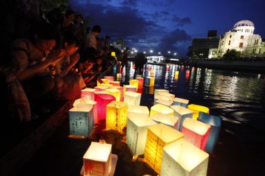 People pray after releasing paper lanterns on a river facing the gutted Atomic Bomb Dome