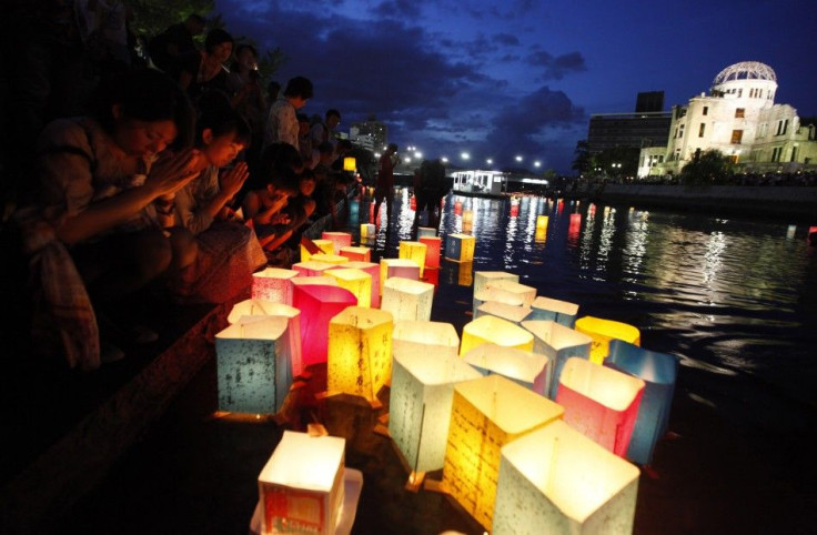 People pray after releasing paper lanterns on a river facing the gutted Atomic Bomb Dome