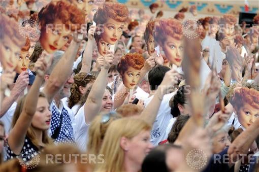 People hold up masks of Lucy Ball during attempt to set a new Guinness world record for most Lucy Ricardo lookalikes assembled in one place, in Jamestown