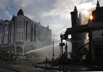 Firemen dowse down buildings set alight during riots in Tottenham, north London, August 7, 2011. Rioters throwing petrol bombs battled police in a economically deprived district of London overnight, setting patrol cars, buildings and a double-decker bus o