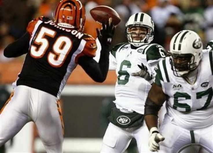 New York Jets quarterback Mark Sanchez (C) throws a pass in front of Brandon Johnson (59) of the Cincinnati Bengals, as lineman Damien Woody (R) tries to block, during the third quarter of their NFL AFC wild card playoff football game at Paul Brown Stadiu