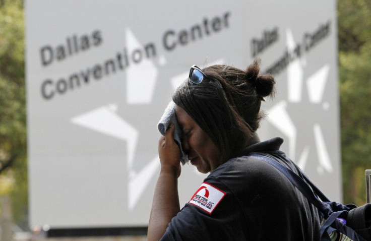 Tamika Davis wipes her face while waiting for a bus in Dallas