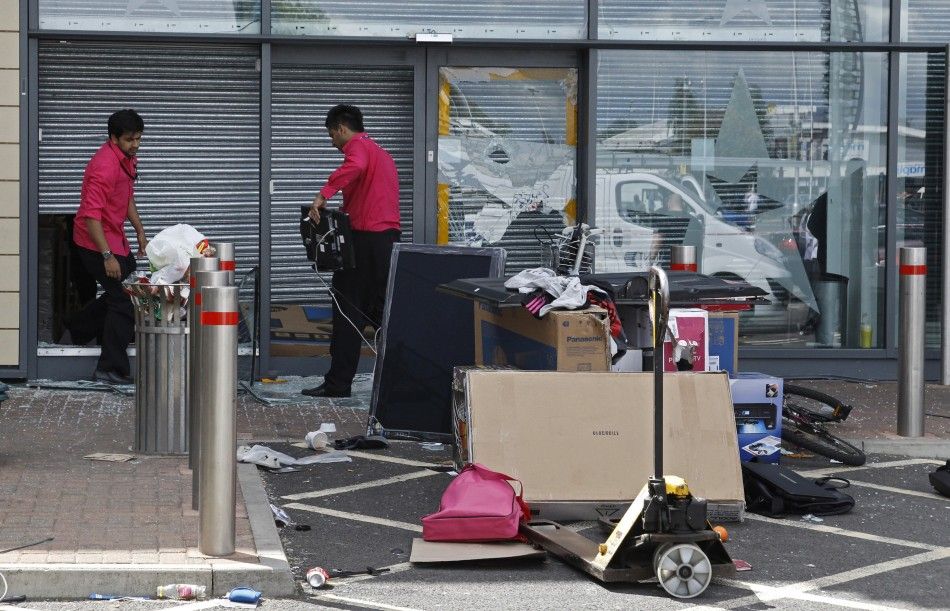 Staff at an electronics goods store clear up after looters damaged the shop at the Tottenham Hale Retail Park in Tottenham, north London.