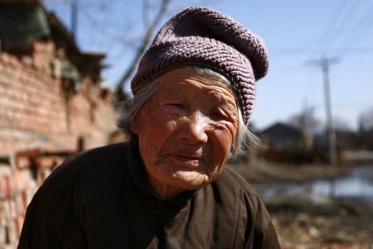 A 92-year-old woman takes a break from sorting corn cobs for selling to a local factory in an effort to make extra income in the village of Jianhua