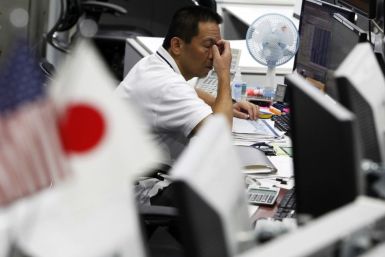 A dealer scratches his face at a foreign exchange trading company in Tokyo