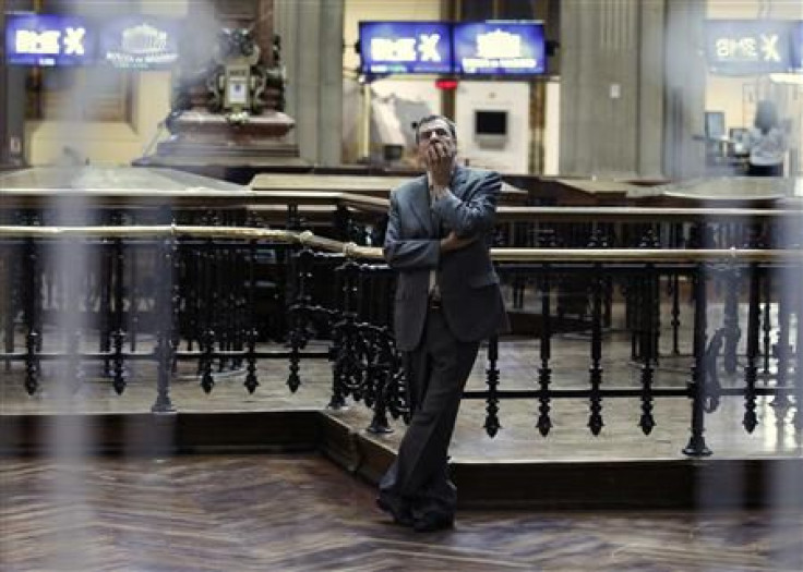 A trader is seen through a window as he looks at screens at the bourse in Madrid