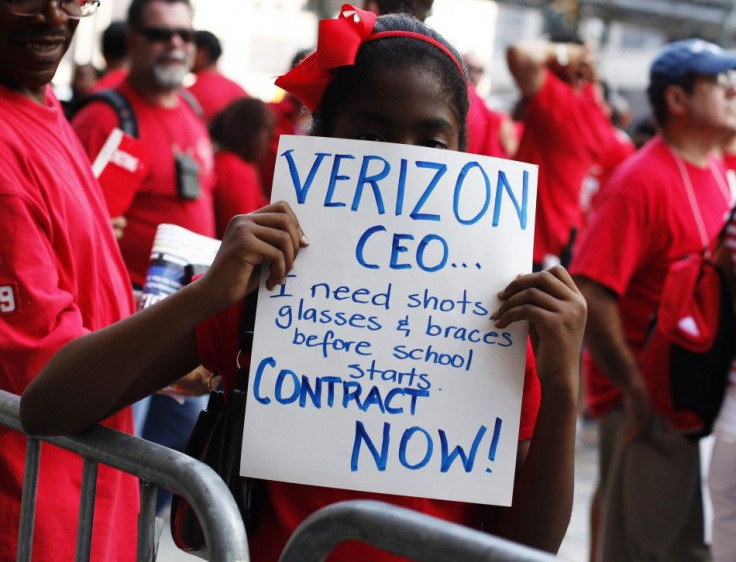 A girl holds a sign as workers rally outside the Verizon headquarters in New York