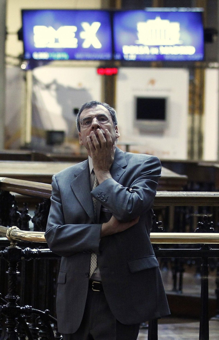 A trader is seen through a window as he looks at screens at the bourse in Madrid