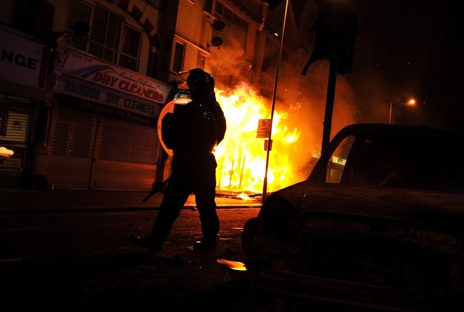 A riot policeman advances past a burning building in Croydon, south London August 8, 2011.