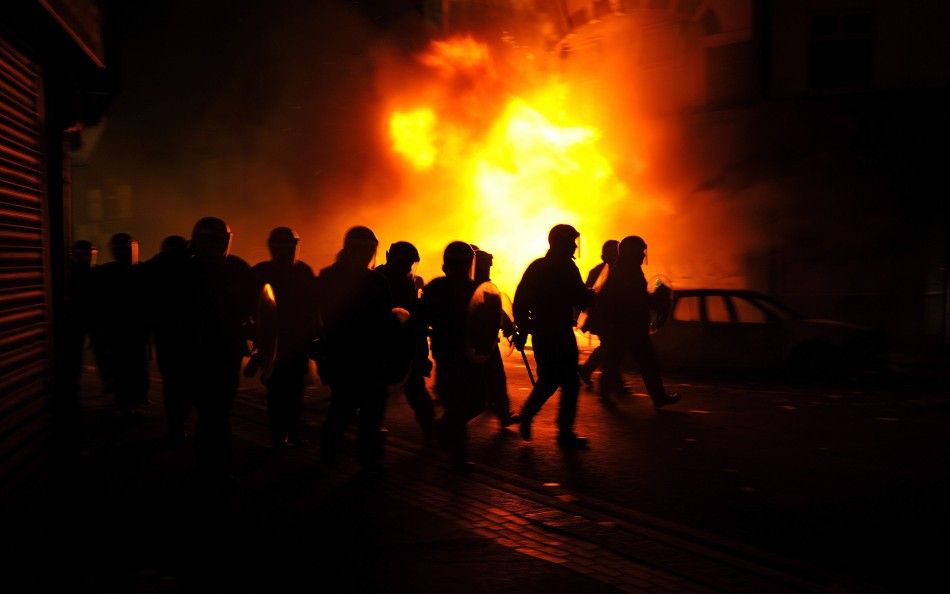 Riot police charge past burning buildings on a residential street in Croydon, south London August 8, 2011