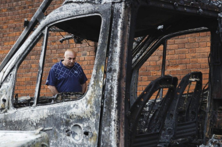 A man looks at a burned out police van set alight during riots in Tottenham