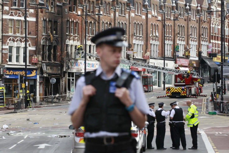 Police officers stand near a burnt out shop in Clapham Junction, in south London