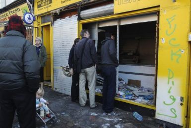 Passersby peer into a looted shop broken into during riots in Hackney in London